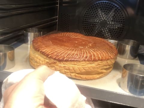 La plaque à pâtisserie contenant le tapis de cuisson, les quatre cercles à mousse et la galette cuite et dorée, est retirée du four