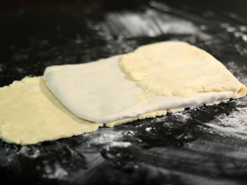 La partie supérieure de la bande de beurre manié est rabattue sur une moitié de la détrempe en forme de rectangle