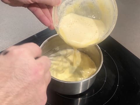 Le mélange à base de jaunes d'oeufs est versé dans la casserole, tout en étant fouetté