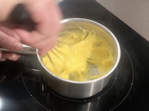 Mélange au fouet de la crème qui est en train de cuire et de s'épaissir dans la casserole