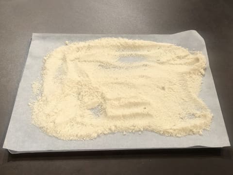 La poudre est étalée sur toute la surface de la feuille de papier sulfurisé qui est placée sur la plaque à pâtisserie