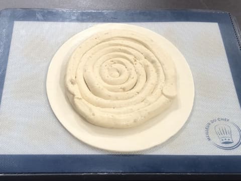 Obtention du disque de pâte feuilletée inversée sur une plaque à pâtisserie recouverte d'un tapis de cuisson en silicone, sur lequel la crème frangipane est pochée en forme de spirale