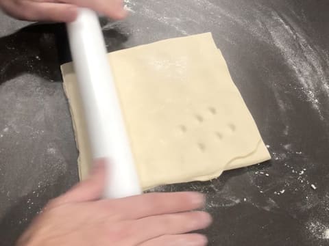 La pâte feuilletée est étalée au rouleau à pâtisserie, sur le plan de travail légèrement fleuré