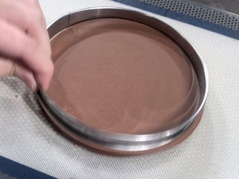 Le cercle inox qui entoure le disque de gianduja sur le tapis de cuisson en silicone est retiré