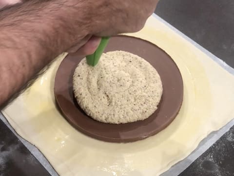 La crème frangipane noisette est pochée sur le disque de gianduja qui est posé au centre du disque de pâte feuilletée