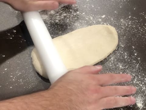 La pâte est abaissée au rouleau à pâtisserie sur le plan de travail fariné