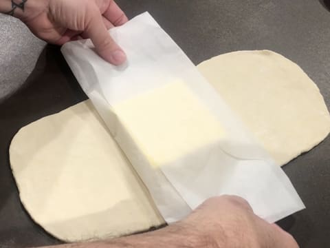 Le beurre de tourage est enveloppé dans une feuille de papier sulfurisé, le tout posé sur l'abaisse de pâte en forme de rectangle