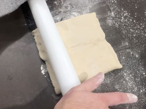 La pâte qui enferme le beurre de tourage est abaissée au rouleau à pâtisserie sur le plan de travail légèrement fariné