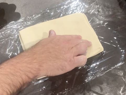 Le pâton rectangulaire qui est posé sur une feuille de papier film, elle même posée sur le plan de travail, est marqué avec deux doigts