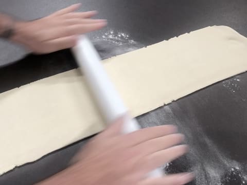 La pâte est abaissée au rouleau à pâtisserie, en une bande trois plus longue que large sur le plan de travail légèrement fariné