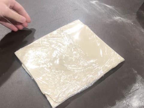 Le pâton est enveloppé dans une feuille de papier film et posé sur le plan de travail