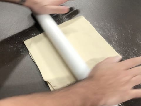 Le pâton rectangulaire est étalé sur le plan de travail à l'aide du rouleau à pâtisserie