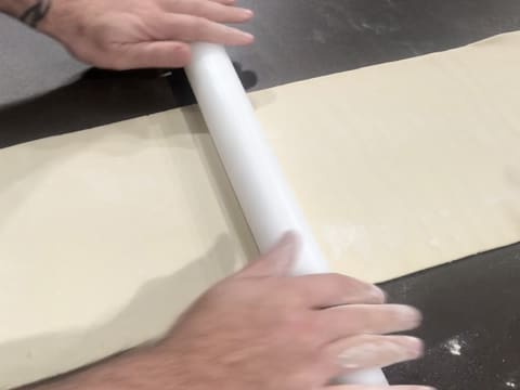 La pâte est abaissée au rouleau à pâtisserie, en une bande trois plus longue que large sur le plan de travail