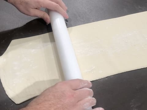 La pâte est abaissée au rouleau à pâtisserie, en une bande trois plus longue que large sur le plan de travail
