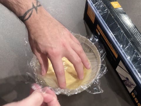 La crème pâtissière noisette qui est dans le saladier, est filmée au contact avec une feuille de papier film