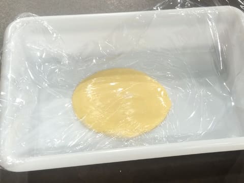 De la crème pâtissière noisette est placée dans un bac alimentaire et filmée au contact avec une feuille de papier film