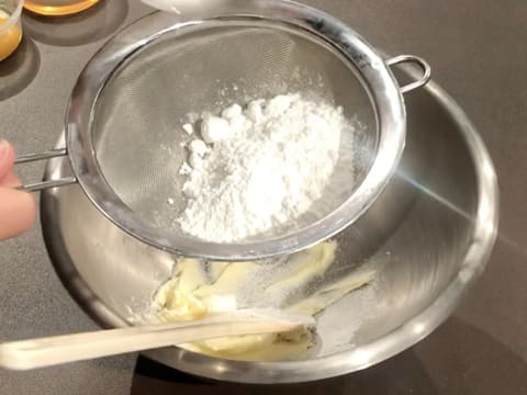 Ajout du sucre glace et de la Maïzena tamisés à la passoire fine, au-dessus du beurre crémeux, dans le cul de poule