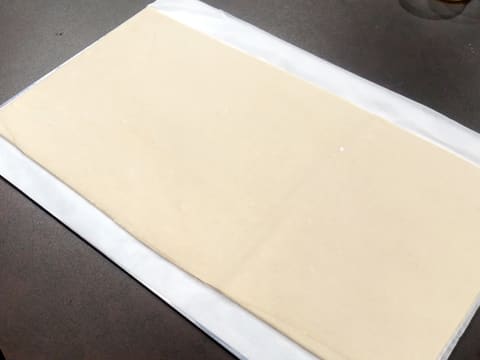La pâte feuilletée abaissée en un rectangle est posée sur le plan de travail 