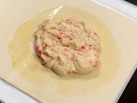 La crème frangipane à la praline rose est pochée sur la pâte feuilletée, au centre du cercle de dorure