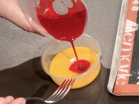 Le colorant liquide rouge est versé dans le jaune d'œuf