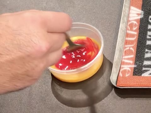 Le colorant rouge est mélangé avec le jaune d'œuf, à l'aide d'une fourchette