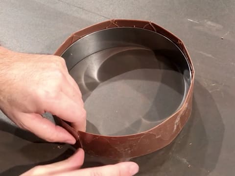 Un ruban adhésif est déposé sur le chocolat afin de le maintenir autour du cercle à mousse