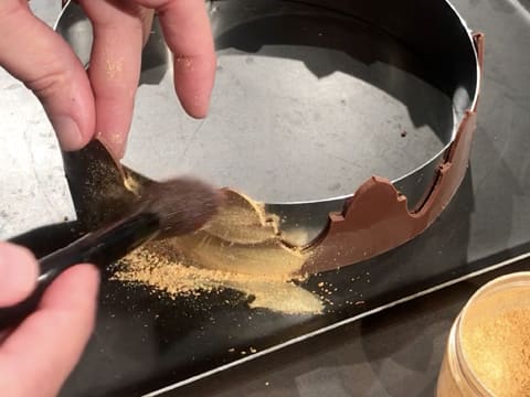 La couronne en chocolat est recouverte de colorant en poudre or avec un pinceau