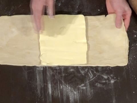 Le beurre aplati en un carré est déposé au centre de l'abaisse de pâte rectangulaire
