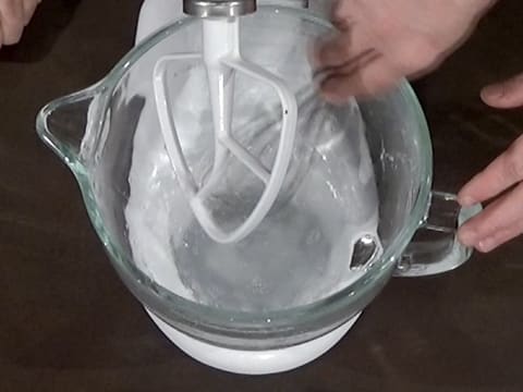 Mélange de l'eau et du sel fin dans la cuve du batteur à l'aide d'un fouet
