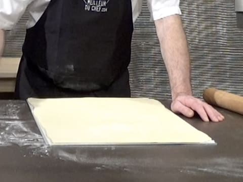 La pâte feuilletée est placée sur la feuille de papier sulfurisé et sur une plaque à pâtisserie