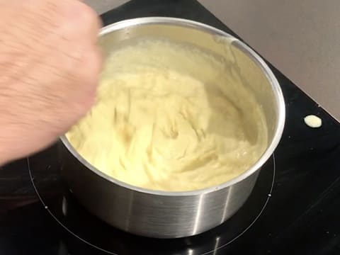 La crème est en train de cuire et de s'épaissir dans la casserole, tout en étant fouettée