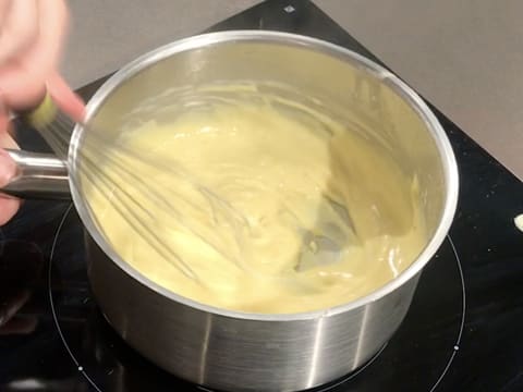 La crème est en train de cuire et de s'assouplir dans la casserole, tout en étant fouettée