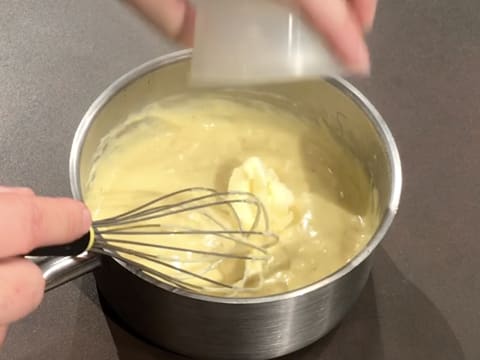 Le beurre est ajouté dans la crème chaude, dans la casserole hors du feu