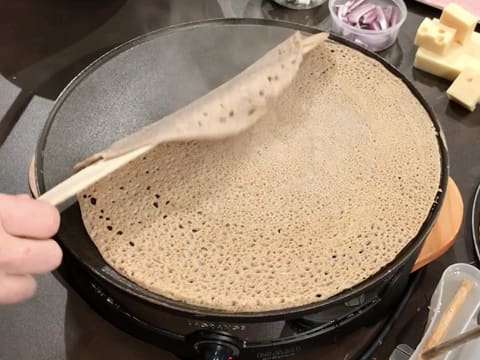 La galette est retournée sur la crêpière électrique, à l'aide de la spatule en bois