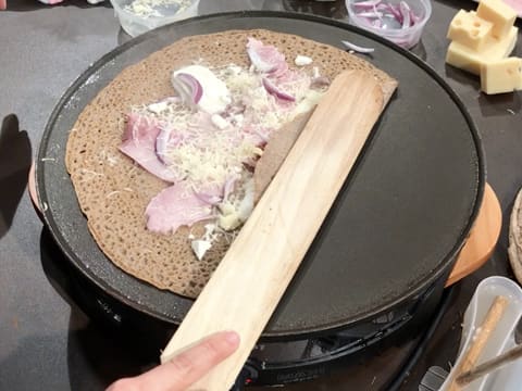 Un côté de la galette est plié avec la spatule en bois