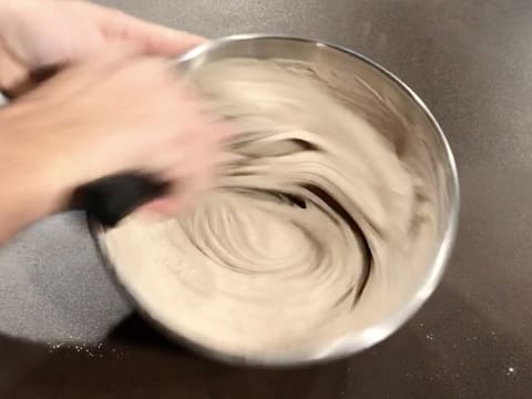 La pâte à galettes est mélangée et homogénéisée avec le fouet, dans le cul de poule