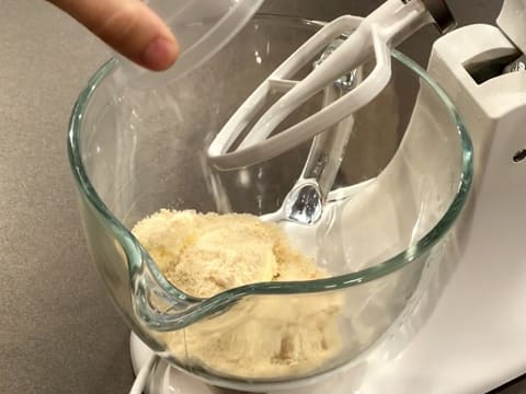 Ajout de la fleur de sel sur la poudre d'amandes, la cassonade et le beurre pommade dans la cuve du batteur électrique qui est muni de l'accessoire feuille