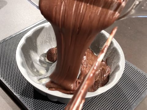 La pâte à gâteau au chocolat est versée dans le moule cannelé à gâteau qui est placé sur une plaque à pâtisserie