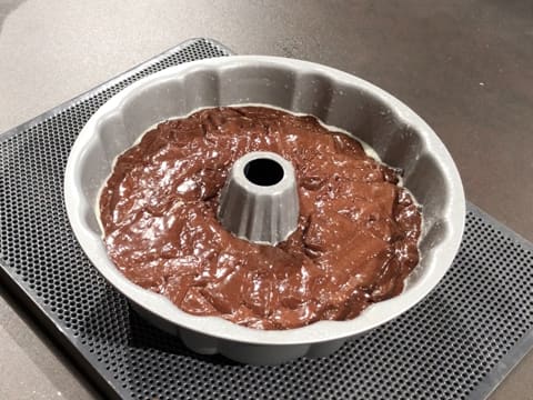 Obtention du moule cannelé à gâteau sur la plaque à pâtisserie, qui est rempli de pâte à gâteau au chocolat jusqu'à mi hauteur