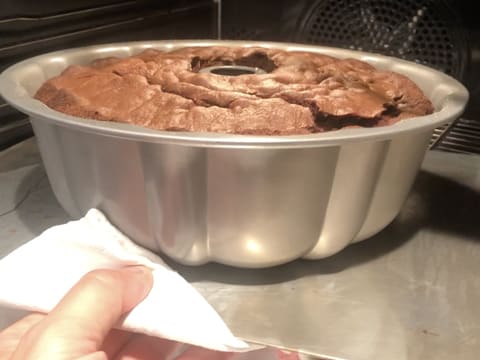 Le moule contenant le gâteau au chocolat cuit et gonflé, est retiré du four avec un torchon