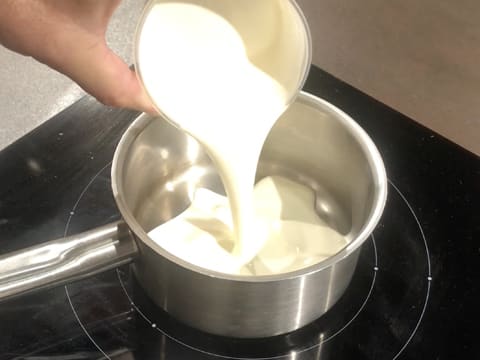 La crème liquide est versée dans une casserole qui est placée sur une plaque de cuisson