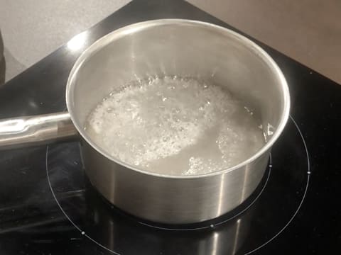 L'eau et le sucre sont en train de bouillir dans la casserole sur la plaque de cuisson