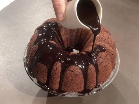 Le glaçage au chocolat est versé sur le gâteau au chocolat qui est placé sur son plat de présentation