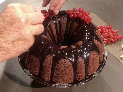 Des grappes de groseilles fraîches sont déposées à la surface du gâteau au chocolat, sur le glaçage au chocolat