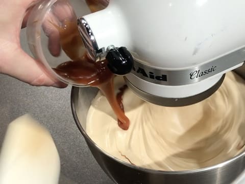 Le caramel au beurre salé est versé sur le mélange oeufs et sucre blanchi, tout en étant fouetté dans la cuve du batteur électrique