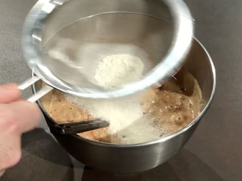 La farine est tamisée dans une passoire fine, au-dessus de la préparation chocolatée dans la cuve du batteur