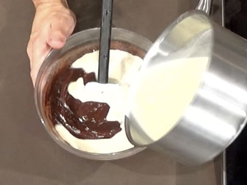 La crème contenue dans la casserole est versée dans le saladier, sur la préparation chocolatée
