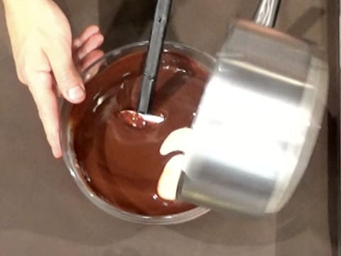 La crème contenue dans la casserole est versée dans le saladier, sur la préparation chocolatée