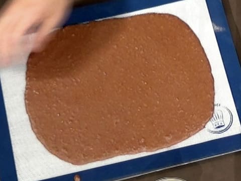 Le tapis de cuisson en silicone contenant le croustillant chocolat, est posé sur le plan de travail
