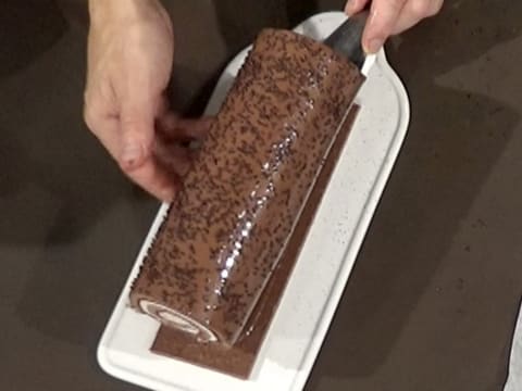 Le gâteau forêt noire est déposé sur la semelle à bûche en croustillant chocolat qui est sur le plat de service
